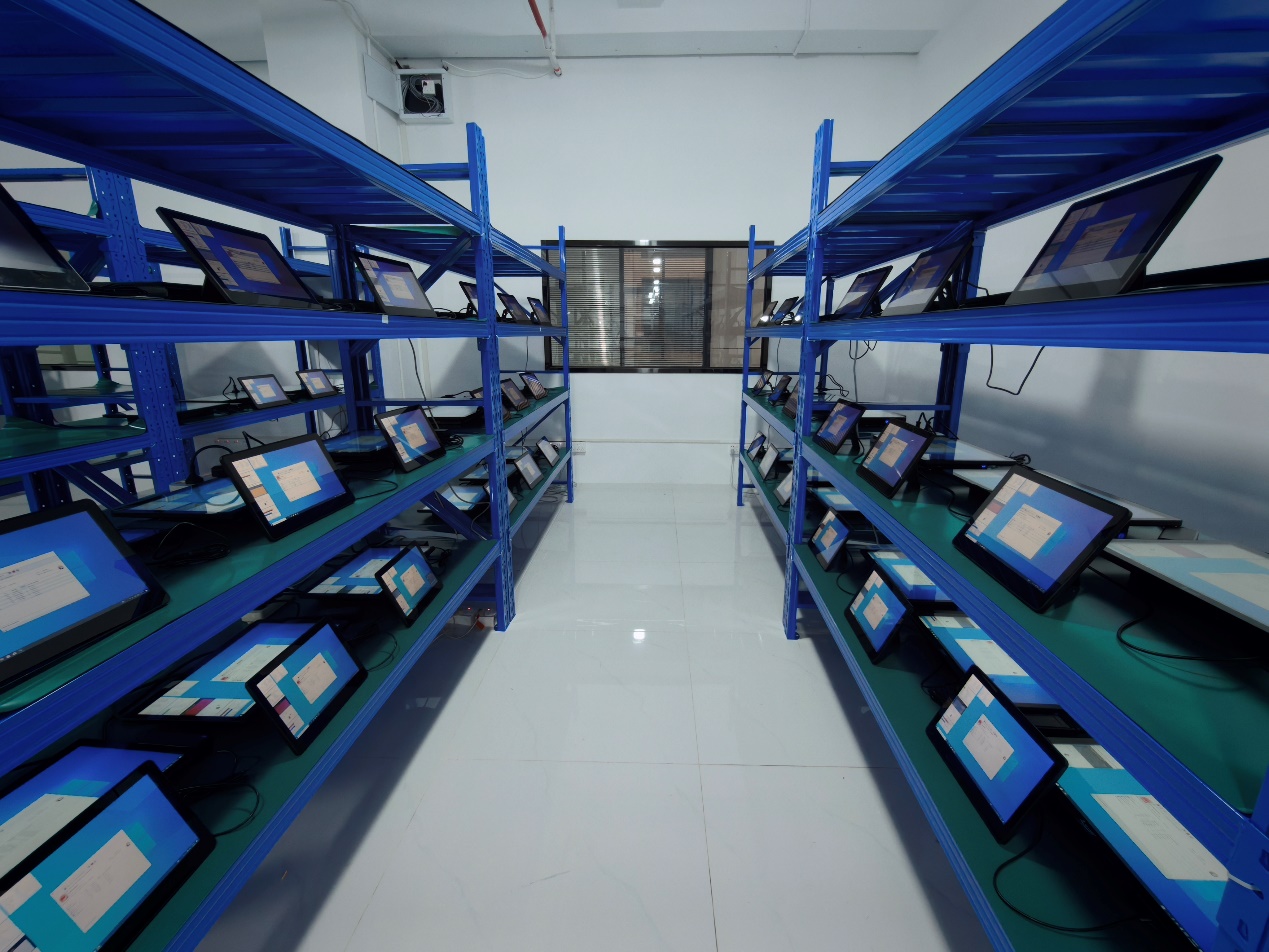 OCOM POS terminals undergoing aging tests on blue shelves in the quality control warehouse
